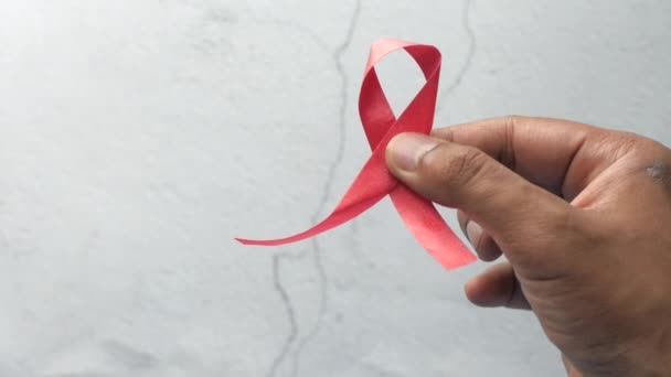 Χέρι κρατώντας κόκκινη κορδέλα HIV με αντίγραφο χώρου — Αρχείο Βίντεο