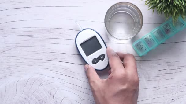 Вид сверху на руку человека, кладущего на стол комплекты для лечения диабета — стоковое видео