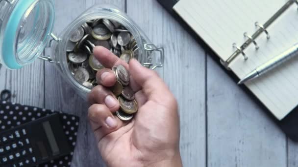 Vrchní pohled na člověka ruční ukládání mincí do sklenice — Stock video