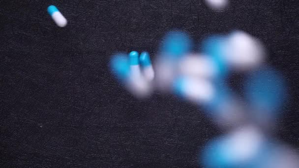 Witte en blauwe capsule druppels op zwarte achtergrond — Stockvideo