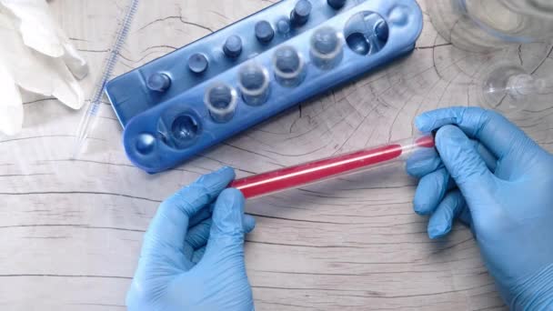 Вид сверху лабораторной техники: пробирка с кровью в руке — стоковое видео