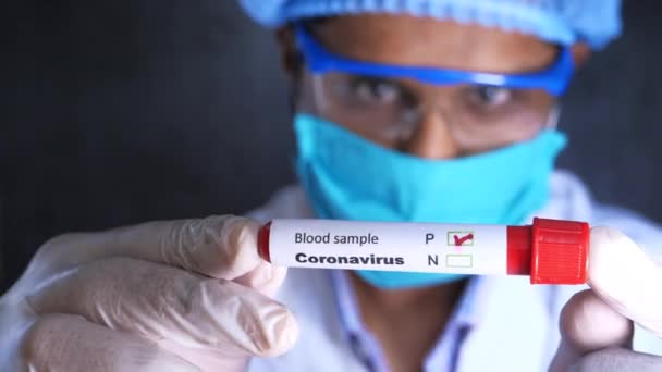 Лаборант в маске и защитном стекле держит пробирку для анализа крови — стоковое видео
