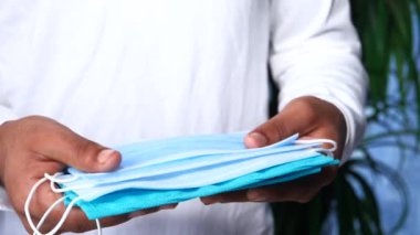 Genç adam koruyucu yüz maskesi tutuyor. Yaklaş. 