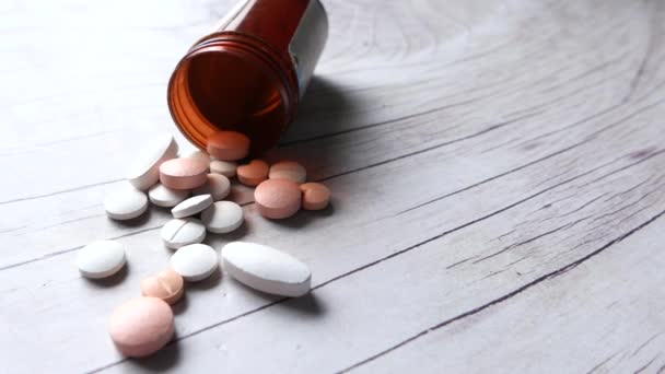 Close up of white pills spilling on wooden background — Stock Video