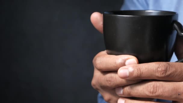 Primo piano dell'uomo mano tenendo tazza isolata sul nero. — Video Stock