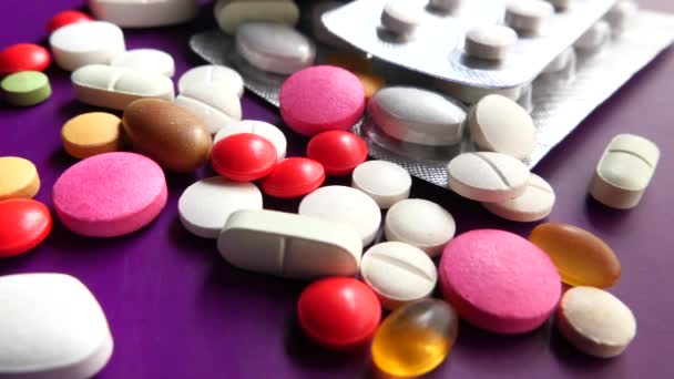 Primo piano di pillole colorate versando su sfondo viola — Video Stock