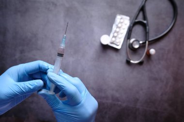 Doktor elinde şırınga tutan tıbbi eldivenler getirdi..