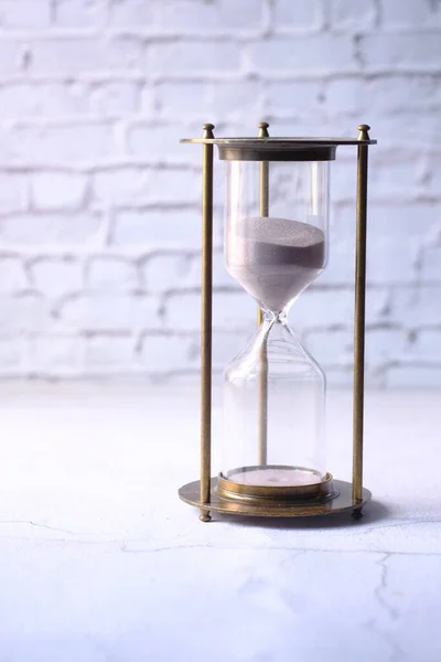 hourglass on table, sand flowing through the bulb of sandglass