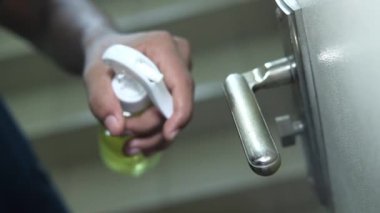 Kapı tokmağını alkol spreyiyle temizliyorum..