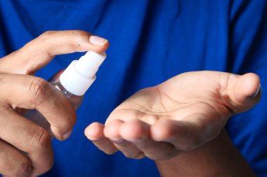 Delikanlının elini dezenfektan spreyiyle kapat..