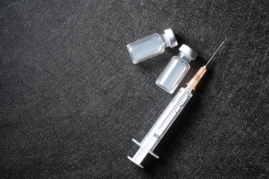 Siyah zemin üzerinde aşıların ve şırıngaların üst görünümü 