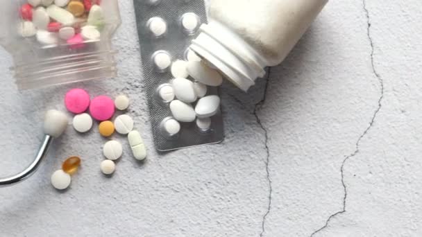 Белые таблетки, пузырь пакет и стетоскоп на белом фоне — стоковое видео