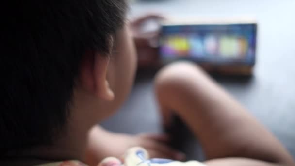 Achteraanzicht van kind meisje kijken cartoon op smart phone. — Stockvideo