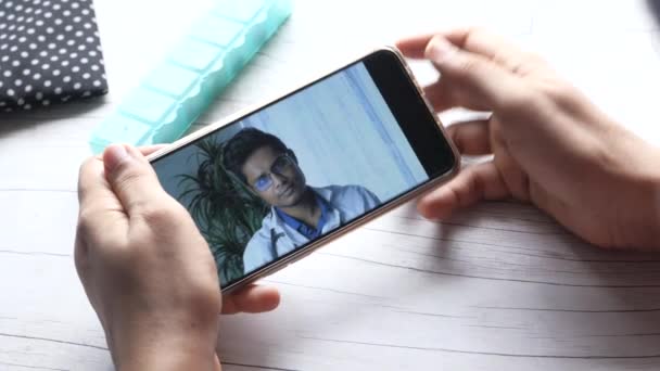 スマートフォンで医師とオンラインで相談する女性の後ろ姿 — ストック動画