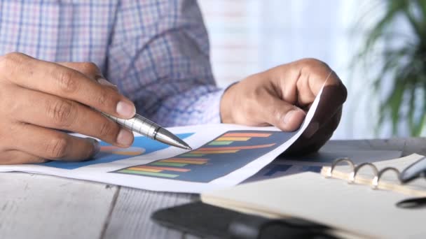 Mão homem com caneta analisando gráfico de barras no papel — Vídeo de Stock