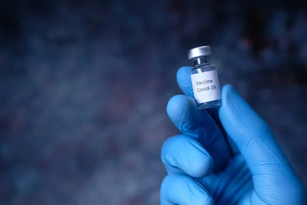 Mano del médico en el guante protector que sostiene la vacuna contra el coronavirus, de cerca — Foto de Stock