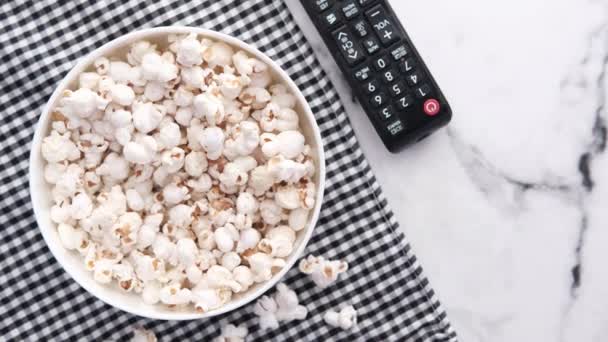 Hoge hoek uitzicht van popcorn en TV afstandsbediening op tafel — Stockvideo
