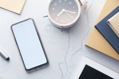 Boş ekranlı akıllı telefon, masa üzerinde saat ve kitap 