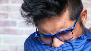 Genç hasta adam burnunu ve ağzını koluyla kapatıyor..