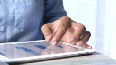 Dijital tablet üzerindeki finansal verileri analiz eden genç adam 