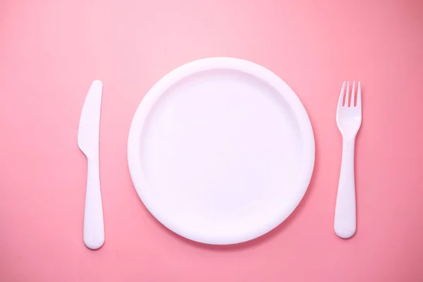 Cutlery and empty plate on pink background top down — Stock Photo, Image