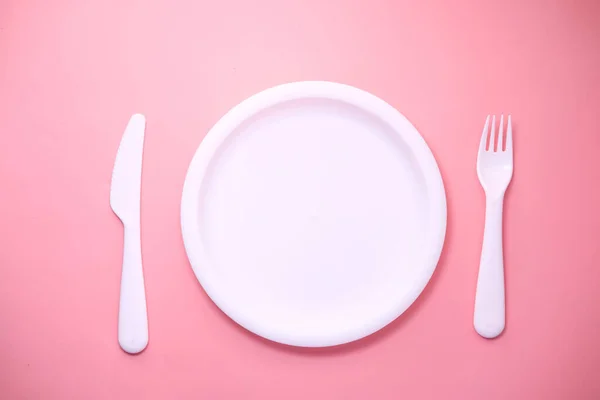 Cutlery and empty plate on pink background top down — Stok Foto