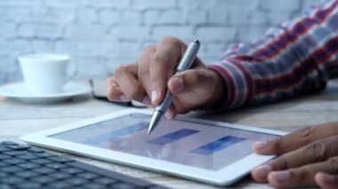 Adam el ile ofis masasında dijital tablet üzerinde çalışıyor, kendi yarattığı grafiği kullanarak. 