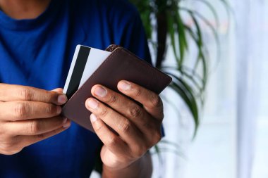 Adamın eli cüzdanından kredi kartını çıkarıyor. 