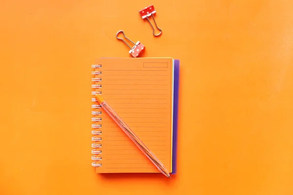 High angle view of open notepad on orange background — Stock Photo, Image