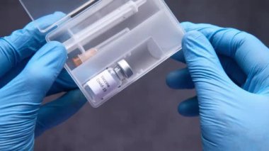 Doktor elinde koronavirüs aşısı olan koruyucu eldivenler getirdi. 