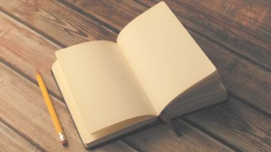 Tahta masada açık bir kitap ve bir kalem. 