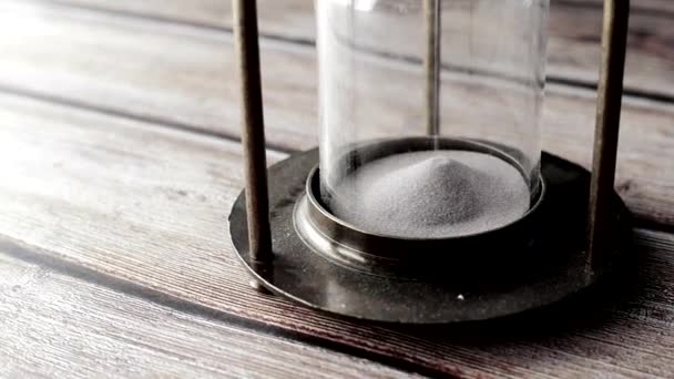 Reloj de arena en la mesa, arena que fluye a través de la bombilla de vidrio de arena — Vídeo de stock