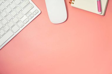 Bilgisayar faresinin üst görünümü, pembe arkaplanda klavye,