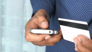 Adamın biri kredi kartını tutuyor ve online akıllı telefon alışverişi yapıyor. 
