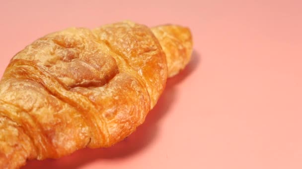 Croissant liso sobre fondo rosa, de cerca — Vídeos de Stock