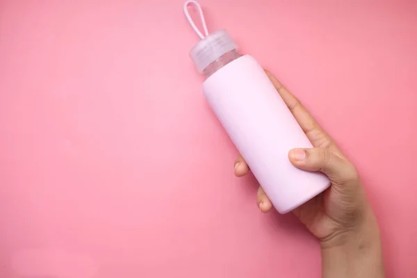 Mão segurando garrafa esporte isolado em rosa, vista superior . — Fotografia de Stock