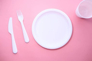 Çatal bıçak takımı ve boş tabak. Pembe arka planda.