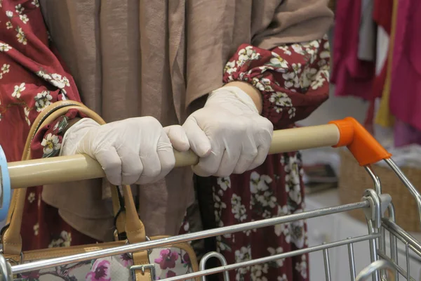 Donna in guanti protettivi che tiene il carrello della spesa. — Foto Stock