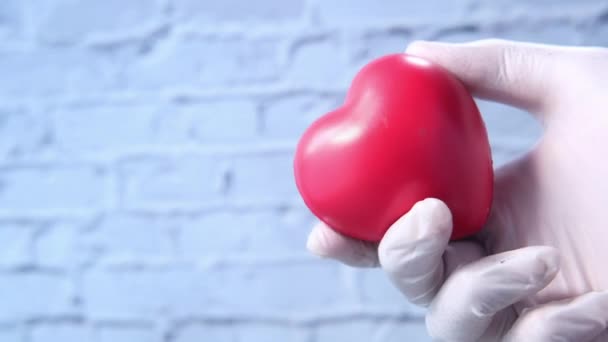 Mano de hombre en guantes protectores sosteniendo el corazón rojo — Vídeo de stock
