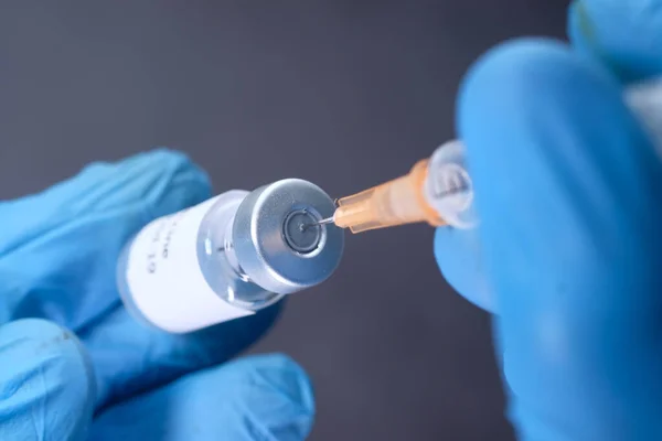 Médico manos en guantes médicos sostiene jeringa y vacuna. — Foto de Stock