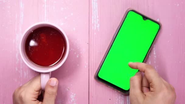 Hoge hoek uitzicht van vrouwen hand met behulp van smartphone en het drinken van koffie — Stockvideo