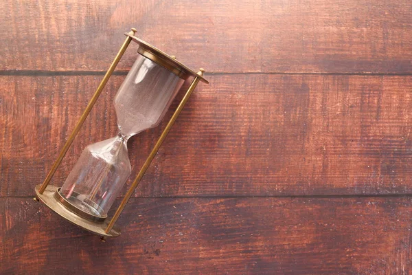 hourglass on table, sand flowing through the bulb of sandglass