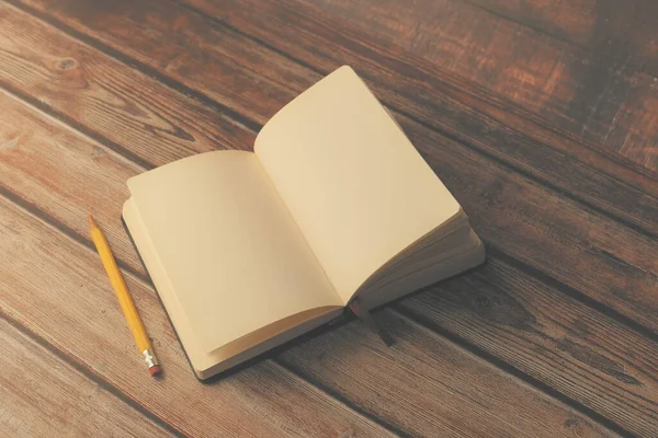 Open boek en een potlood op houten tafel — Stockfoto