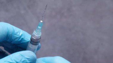 Doktor elinde şırınga tutan tıbbi eldivenler getirdi..