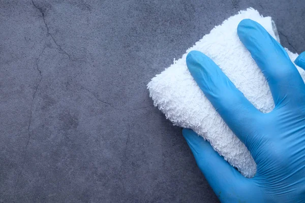 手拿着蓝色橡胶手套用布擦拭桌子 — 图库照片