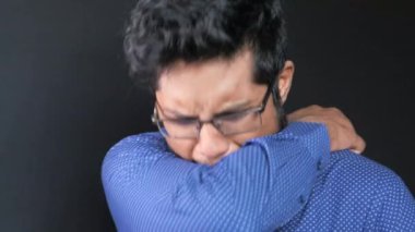 Genç adam burnunu ve ağzını koluyla kapatıyor..