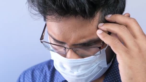 Seorang pemuda dengan topeng pelindung di wajah menderita sakit kepala — Stok Video
