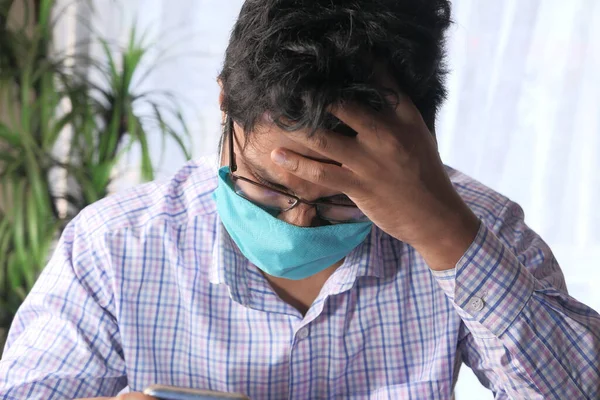 Een jonge Aziatische man met een beschermend masker in het gezicht verdrietig voelen — Stockfoto