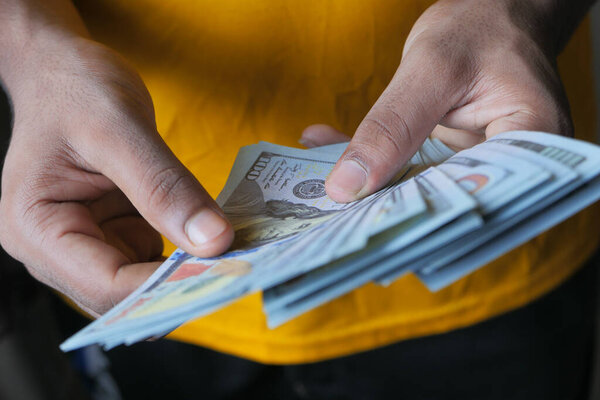 Крупный план руки человека, считая 100 долларов наличными 