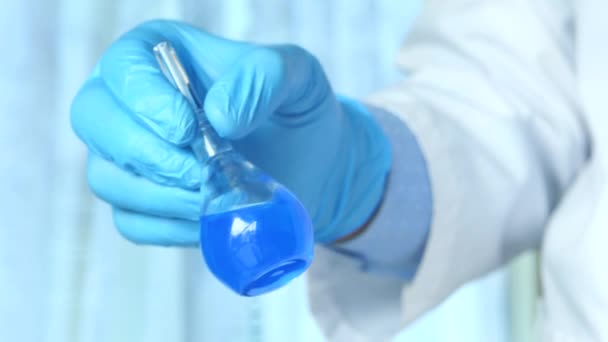 Hand van wetenschapper holding lab glaswerk close-up — Stockvideo